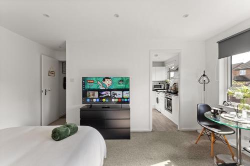 a bedroom with a bed and a kitchen with a tv at Private Studio Apartment In Dartford DA1 Free Parking TFL Zone 6 in Slades Green