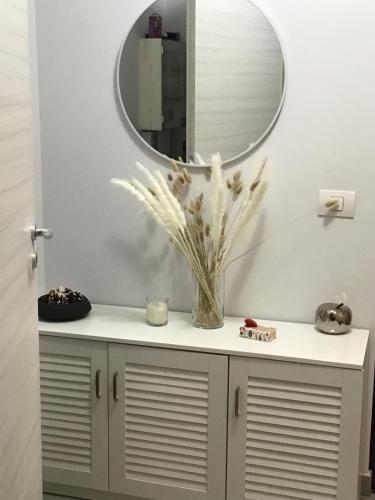 a bathroom vanity with a mirror and a vase with flowers at La casa in Tielt