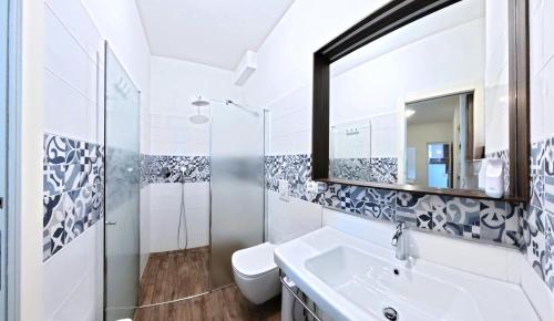 a white bathroom with a sink and a mirror at Oasi Da Vinci Apartments Lake Garda View in Tignale