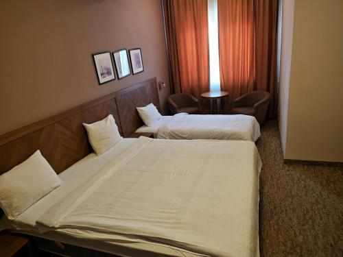 a hotel room with two beds and a chair at Hotel Emka in Tetovo