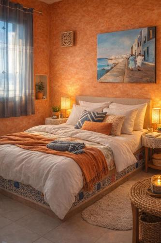 a bedroom with a large bed with a painting on the wall at Dar El Amen Appartements in Mahdia