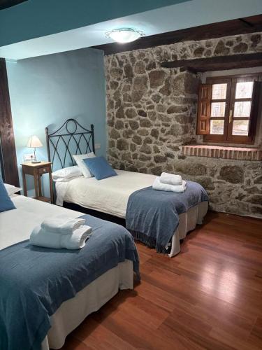 a bedroom with two beds and a stone wall at La Carbonería in Béjar