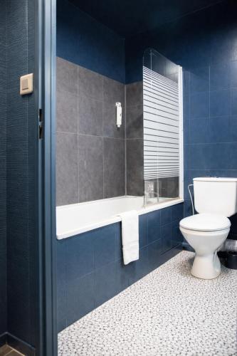 a bathroom with a toilet and a mirror and blue walls at The Originals City, Hôtel Ascotel, Lille Est Grand Stade in Villeneuve d'Ascq
