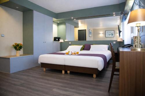 a bedroom with a bed and a table in a room at The Originals City, Hôtel Ascotel, Lille Est Grand Stade in Villeneuve d'Ascq