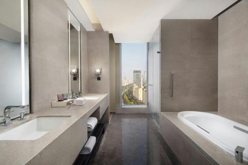 a bathroom with two sinks and a tub and a window at Courtyard by Marriott Luoyang in Luoyang