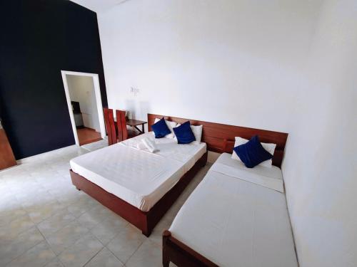 a bedroom with two beds with blue pillows at Jegers Villa in Negombo