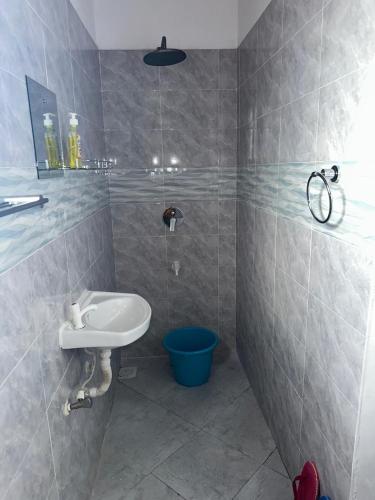 a bathroom with a sink and a blue bucket at Munaa House Wiyoni in Lamu