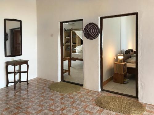 a room with two mirrors and a bedroom with a bed at House on the beach in Jambiani