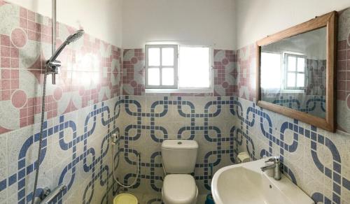 a bathroom with a toilet and a sink and a mirror at House on the beach in Jambiani