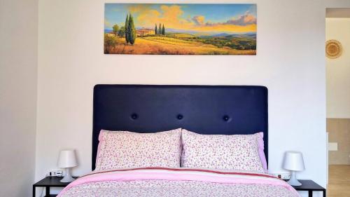 a bedroom with a bed with a painting on the wall at Maya Suite & Garden in Sarteano