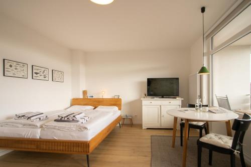 a bedroom with a bed and a table and a tv at Sylt for Friends in Hörnum