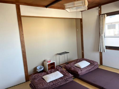 a room with two beds and a window at ゲストハウスまちかど Guest House MACHIKADO in Ibusuki