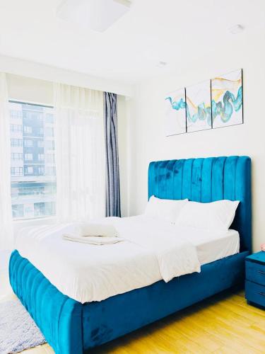 a blue bed in a room with a window at Urban Homes-Two Bedroom Near JKIA Airport in Nairobi