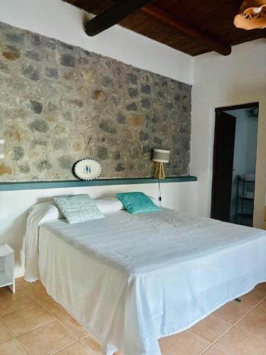 a bedroom with a bed with a stone wall at Dépendance Liscio in Filicudi