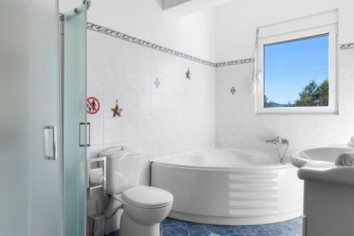 a white bathroom with a tub and a toilet and a sink at Agathi Sun Set in Rhodes Town
