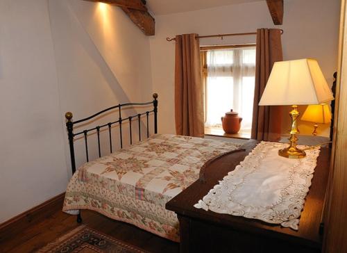 a bedroom with a bed with a lamp and a window at Upper Cottage, Brixham in Brixham