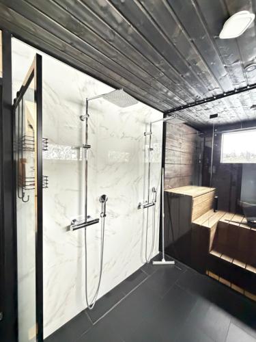 a bathroom with a shower stall and a tub at Modern Villa JoenPolku Ruka With jacuzzi, sauna and scenic views in Ruka