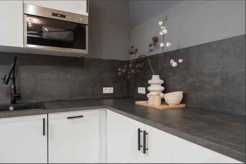 a kitchen with white cabinets and a vase on the counter at Suite w kitchen acces,Den bosch- Oss, near train in Oss