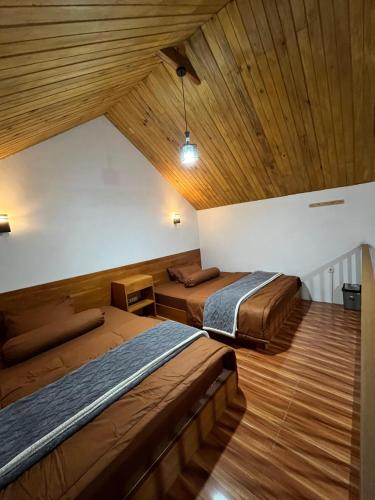 two beds in a room with wooden ceilings at Asokabin House in Diyeng