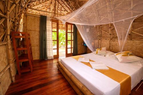 a bedroom with a bed with a mosquito net at Dos Playa EcoCamp Daracoton Island in El Nido