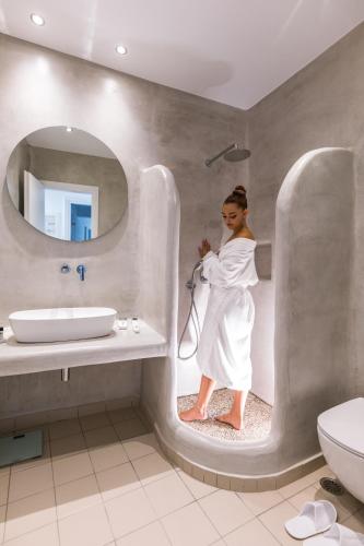 a woman standing in a bathroom with a shower at Naxos Grand Hotel in Agios Prokopios