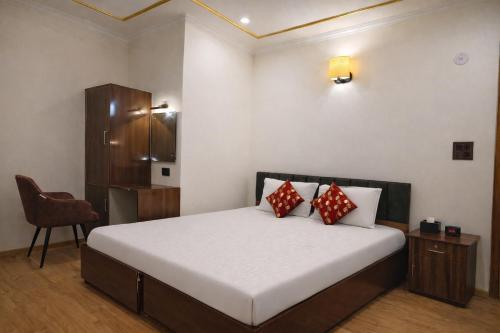 a bedroom with a bed with red pillows and a chair at RH Guest House Leh in Leh