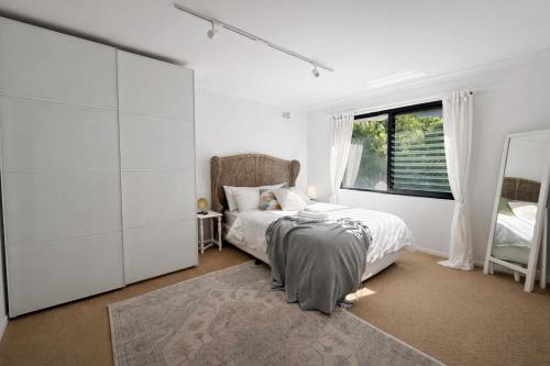 a bedroom with a bed and a large window at Coastal Stay in Cronulla