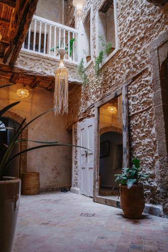 a room with a stone wall with a door and a chandelier at Authentic Riad - Sea View & Rooftop Spa in Essaouira