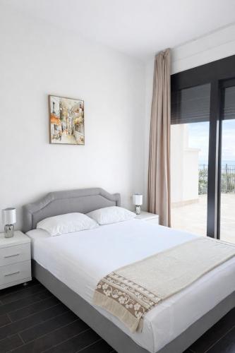 a white bedroom with a large bed and a window at Sea View Residence with Pool & Private Terrace in Krstac
