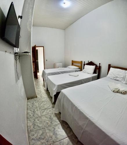 a room with three beds and a flat screen tv at Hotel e Pousada França in Manhã
