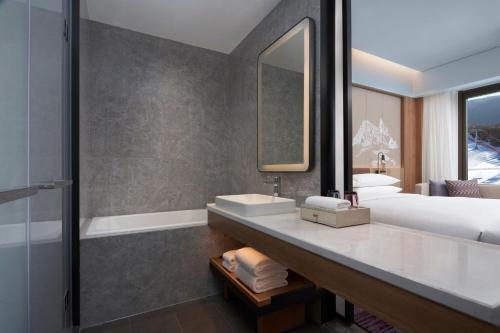a bathroom with a sink and a bed and a tub at Courtyard by Marriott Chongli in Zhangjiakou