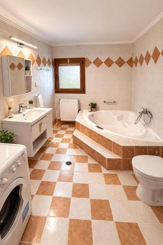 a bathroom with a tub and a toilet and a sink at Melitta Villa in Ágios Ioánnis