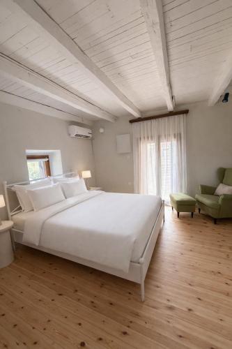 a bedroom with a large white bed and a chair at Melitta Villa in Ágios Ioánnis