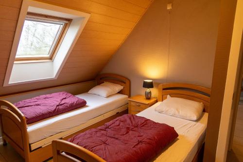 two beds in a small room with a window at 't Ooievaarsnest in Veurne