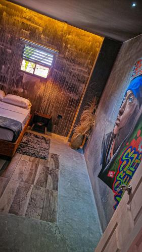 a room with a bed and a painting on the wall at Urban Hostel Pool & Garden in San Gil