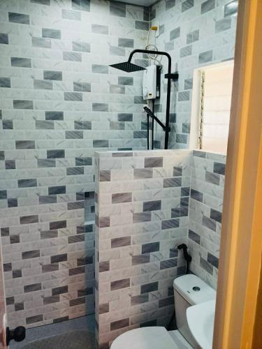 a bathroom with a toilet and a tile wall at Coco Grove Nature Resort in Himensulan