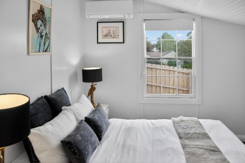 a white bedroom with a bed and a window at Cedar Cottage Daylesford in Daylesford