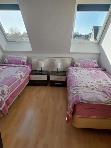 two beds in a room with two windows at Pension-Auszeit in Giesen