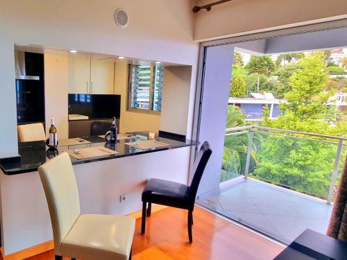 a kitchen with a bar with a view of a balcony at Spacious Summer Fresh Family Apartment with Panoramic Sea Views in Funchal in Funchal