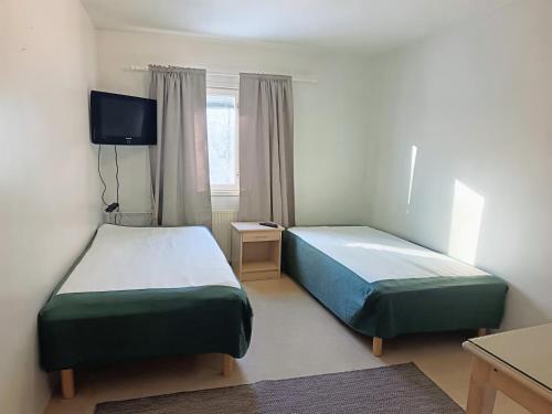 two beds in a small room with a tv at Nivan Majoitus Nivan koulu in Joensuu