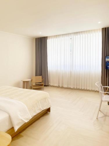 a white bedroom with a bed and a chair at Quies Hotel in Krabi