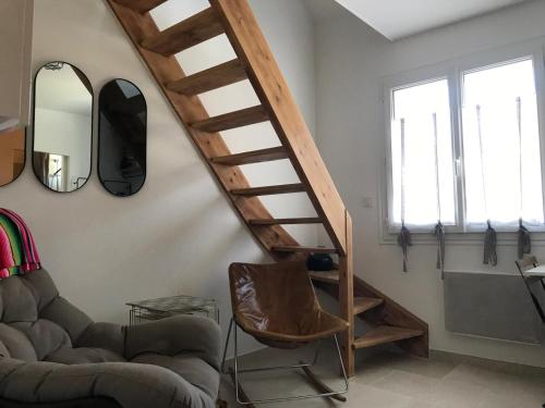 a living room with a wooden staircase and a chair at Gipsy Chic Duplex on the beach in Carolles