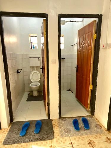 a bathroom with a toilet and blue slippers on the floor at Jenka homes in Kitui