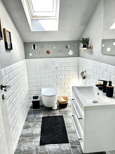 a white bathroom with a toilet and a sink at Urban Gold Apartment in Mostar