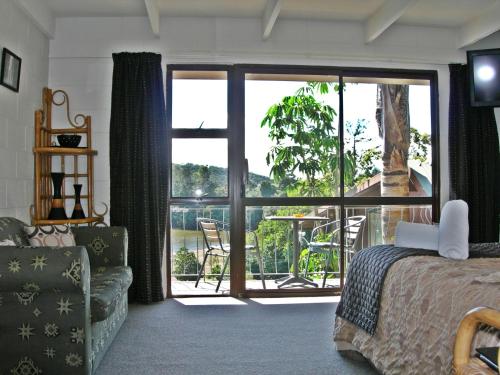 Schlafzimmer mit einem Bett und Blick auf einen Balkon in der Unterkunft Waterfalls Estate - Falls Motel & Waterfront Campground in Paihia