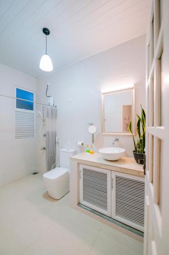 a white bathroom with a toilet and a sink at Heaven R in Kandy