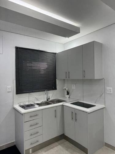 a kitchen with white cabinets and a sink and a window at DECADE Self-catering in Swakopmund