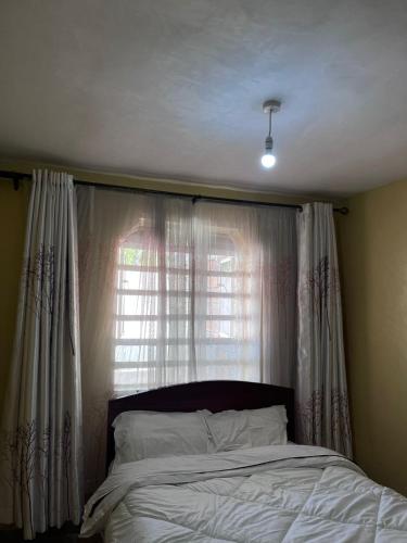 a bedroom with a bed and a window with curtains at Golf B&B in Nyahururu