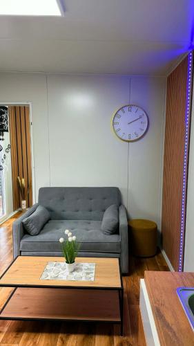 a living room with a couch and a clock on the wall at Domek modułowyBursztynek in Rewa