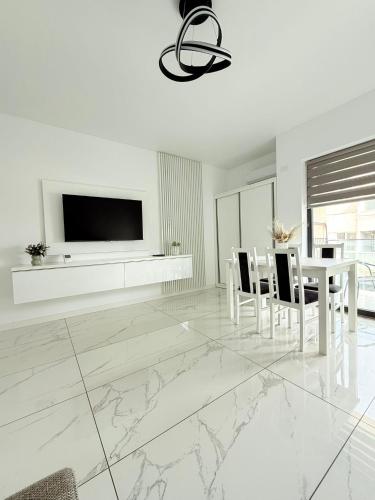 a white living room with a table and a tv on a wall at Apartamente & Studiouri Melia Eforie Nord in Eforie Nord